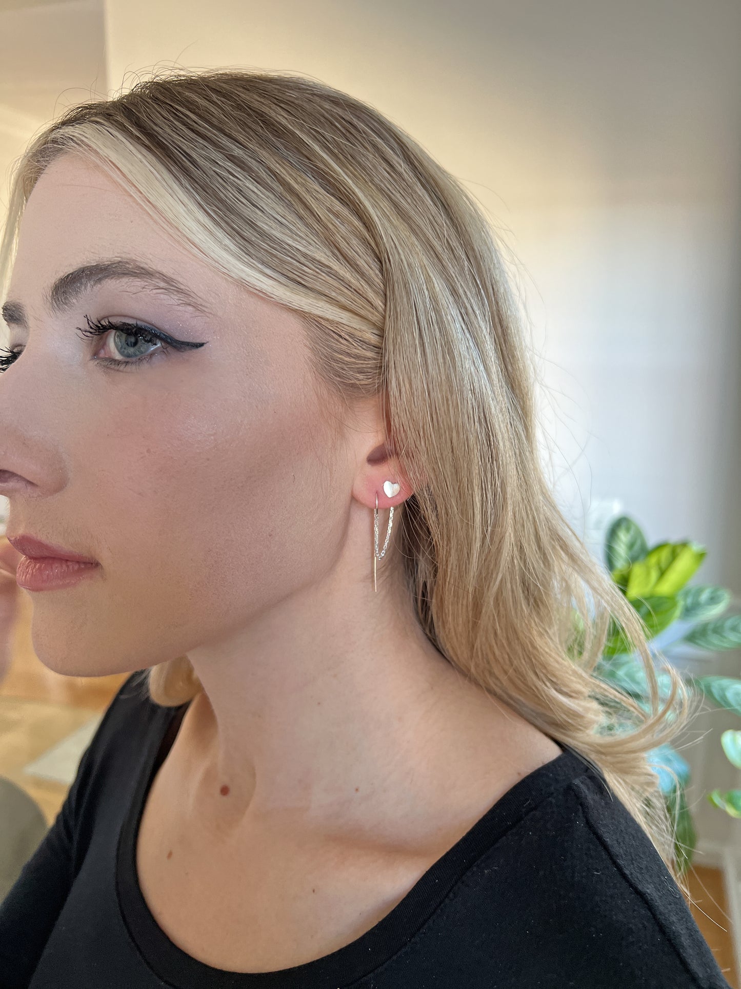 model wearing double hole connected earrings with sterling silver heart studs