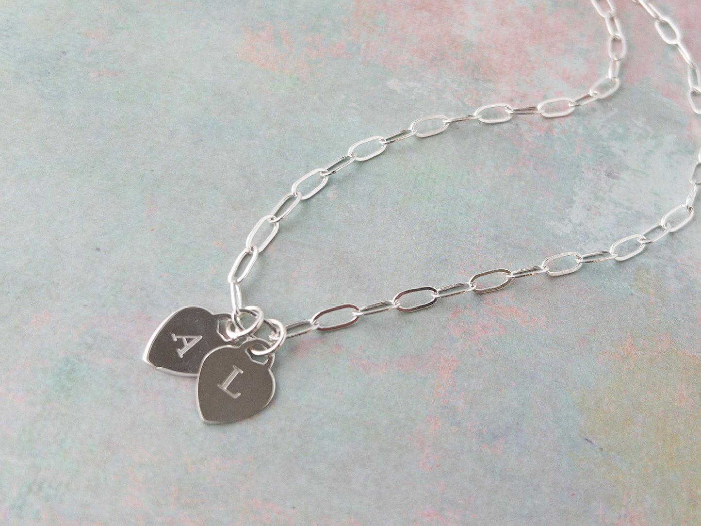 close up of sterling silver heart charms with engraved letters