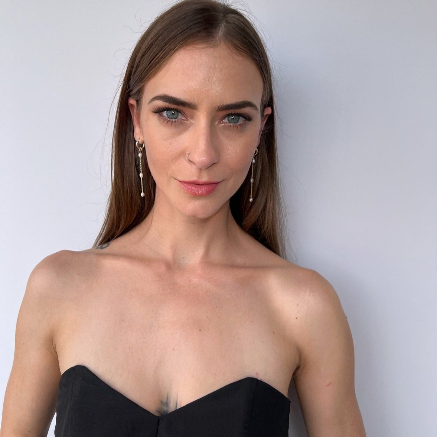 model wearing long pearl dangle earrings on huggie hoops
