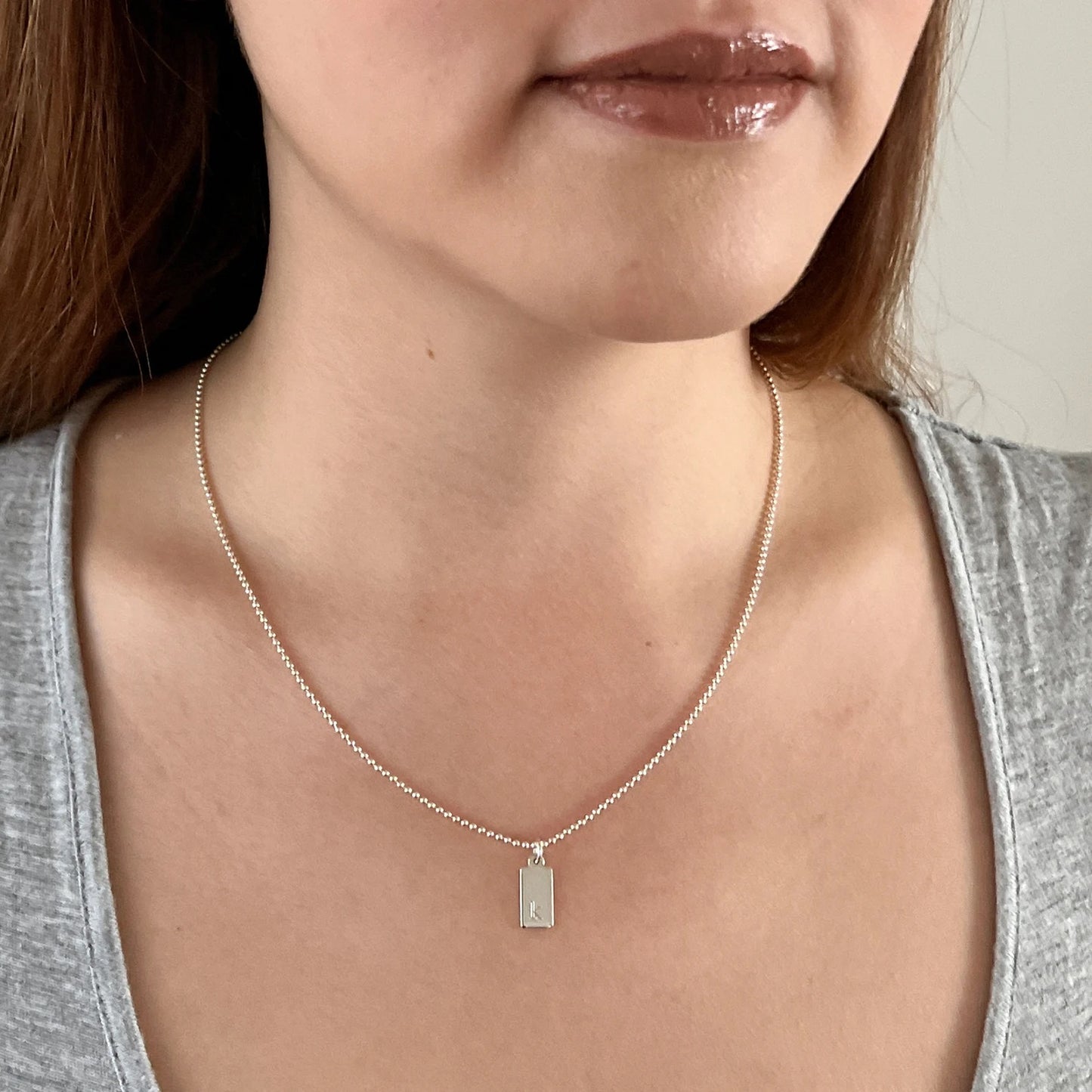 model wearing tiny dog tag necklace in sterling silver