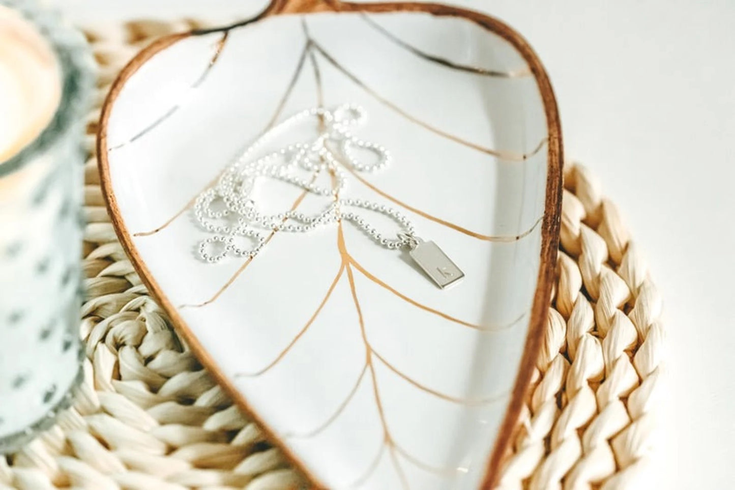 tiny dog tag necklace on beaded chain in dish