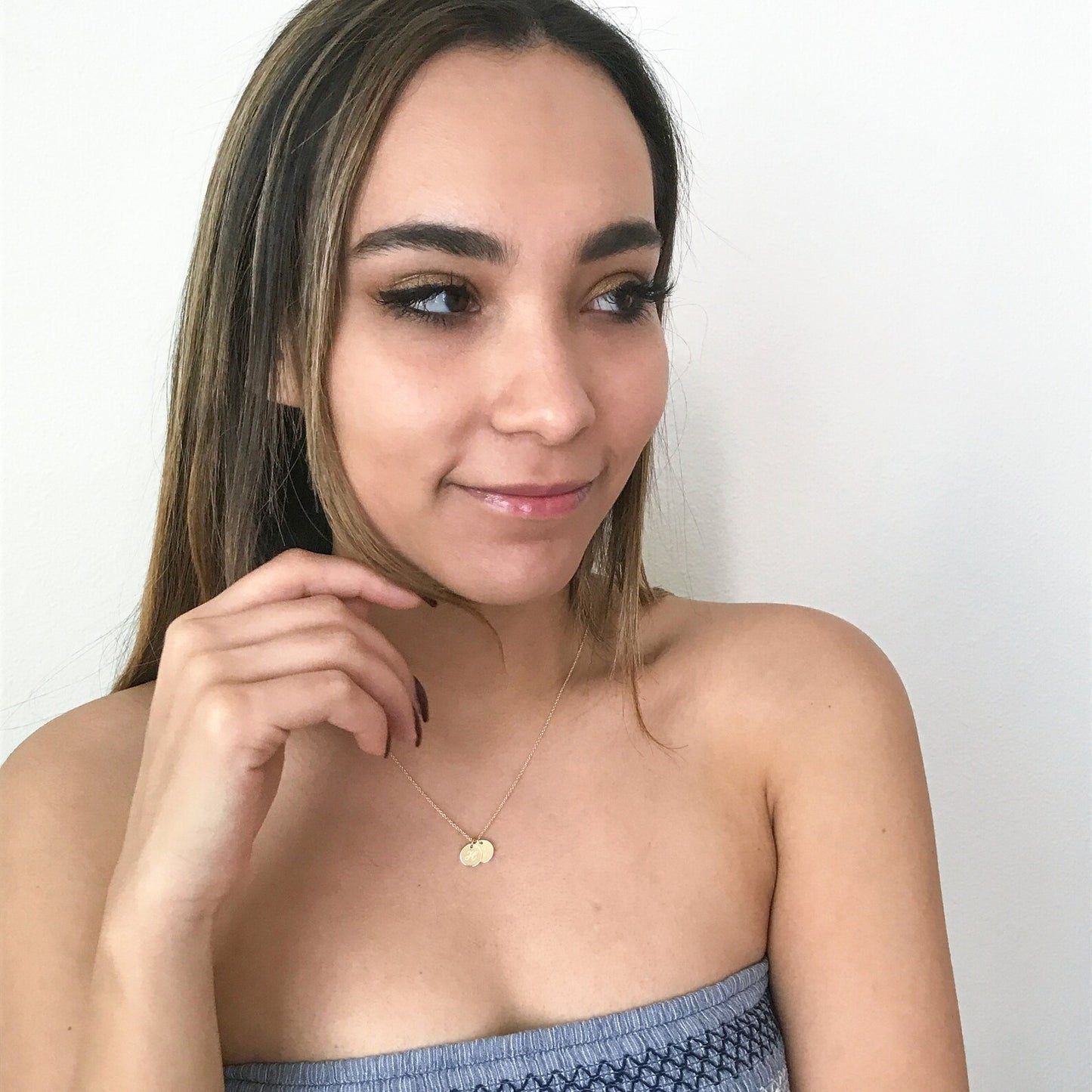 model wearing small engraved charm necklace