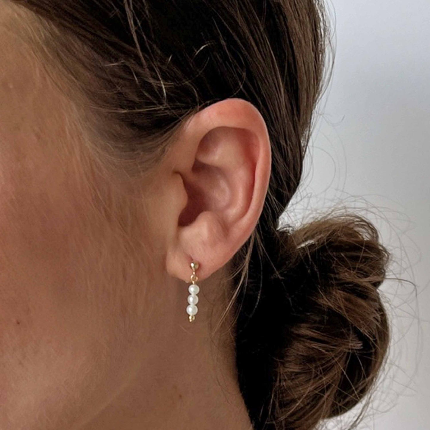 model wearing pearl drop earrings in 14k gold fill with small stud and 3 tiny pearls