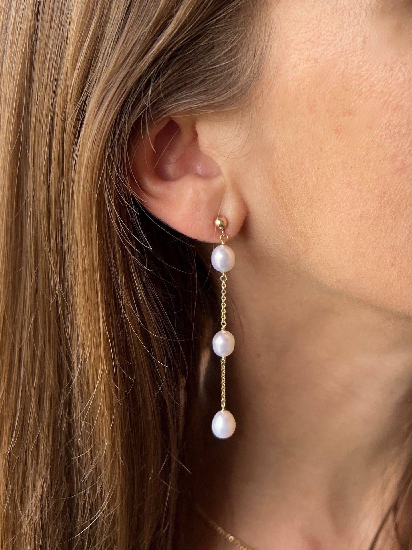 model close up of 14k gold filled stud earrings with long pearl dangles