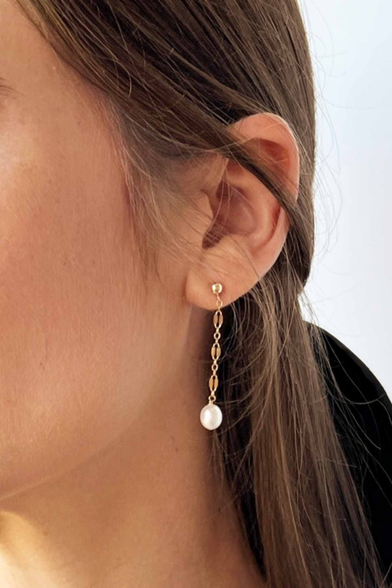 close up of model wearing stud earrings with dangle pearls