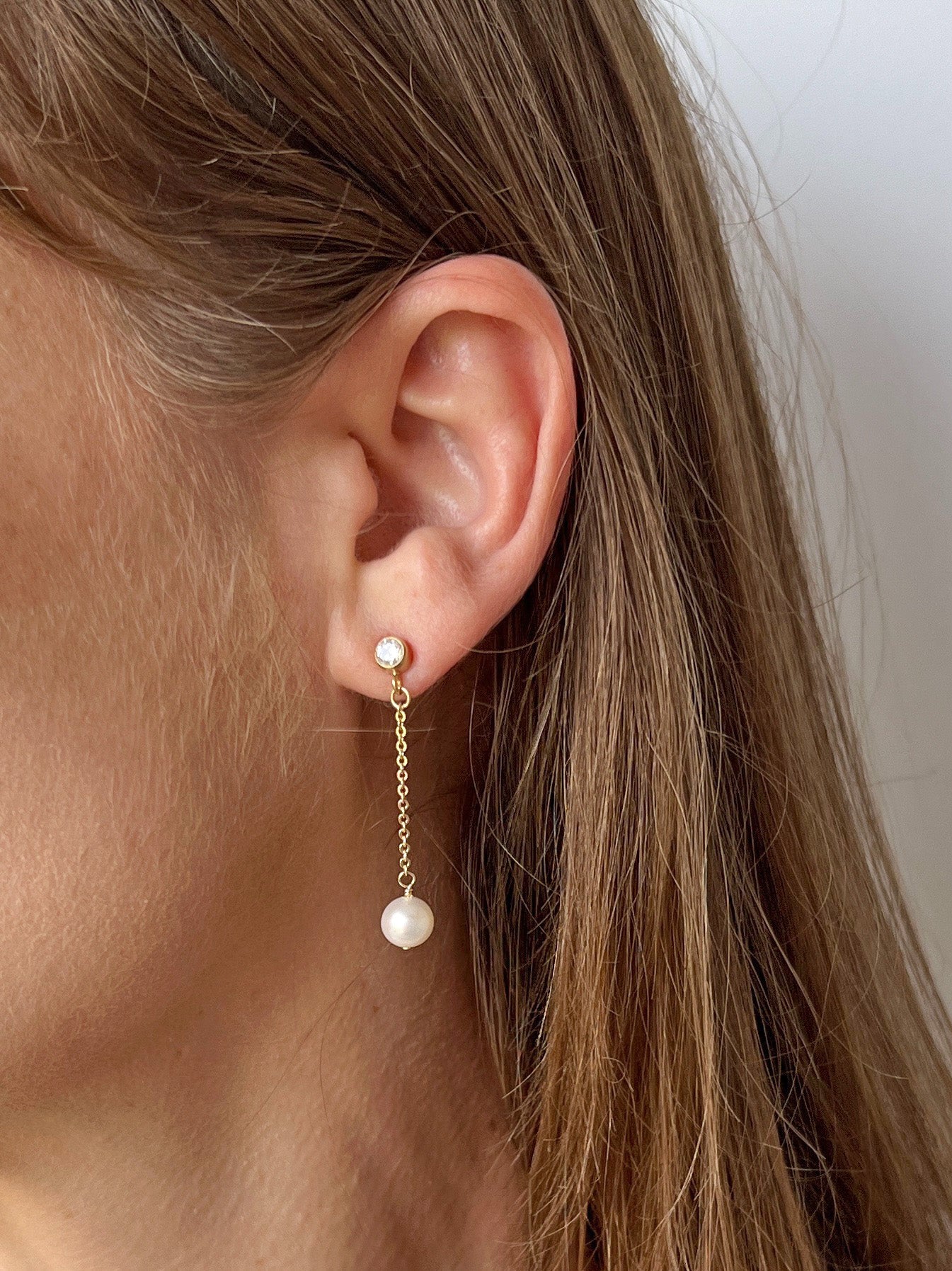 close up of Lucia Pearl stud earrings with cubic zirconia on 14k gold filled