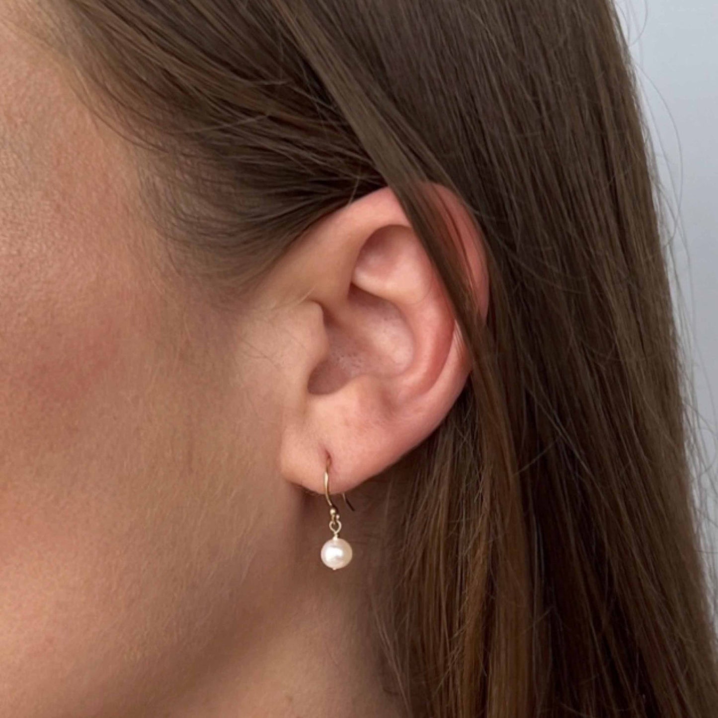 close up of Lucia freshwater pearl earrings on model