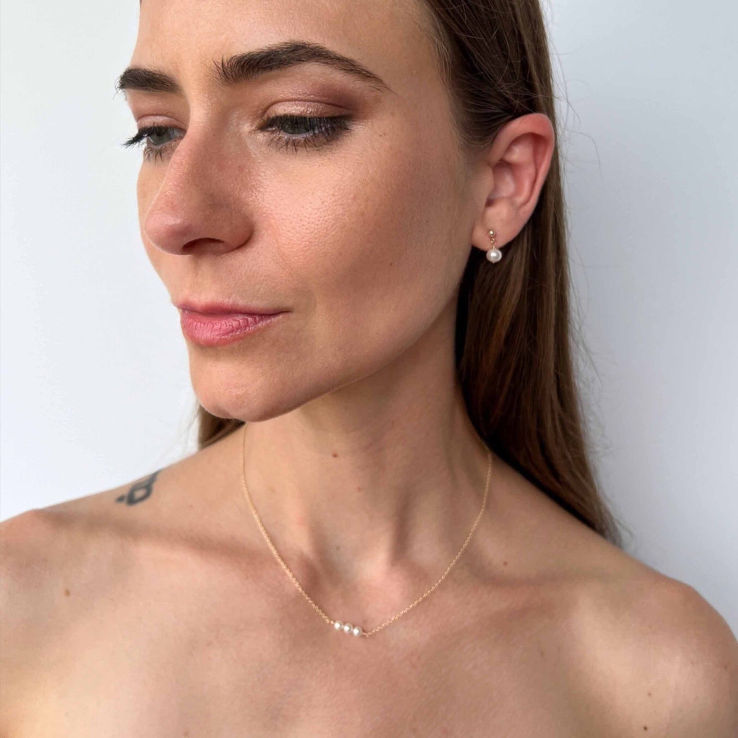 model wearing Lucia dainty pearl necklace with 3 pearls on gold chain