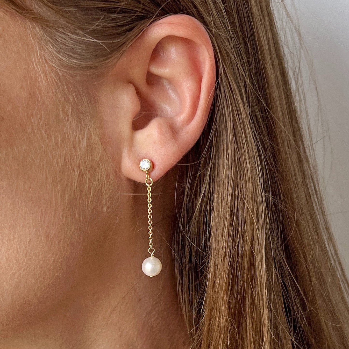 close up of model wearing Lucia Pearl Drop Earrings with CZ Stud