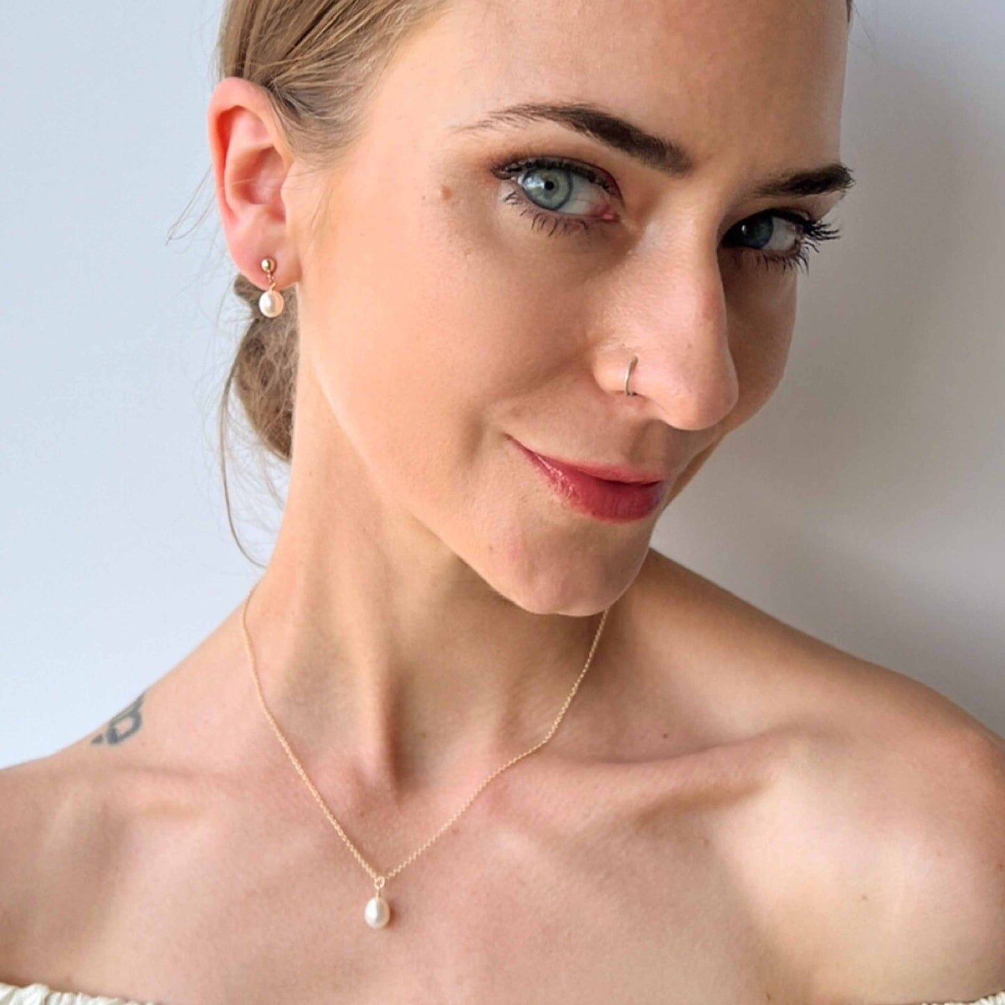 model wearing necklace and earrings set of Single pearl necklace and pearl drop earrings from the Nicola collection