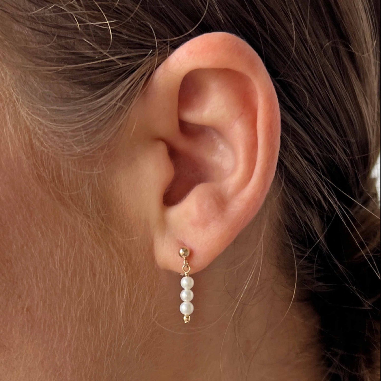 close up of 3 pearl dangle earrings on model