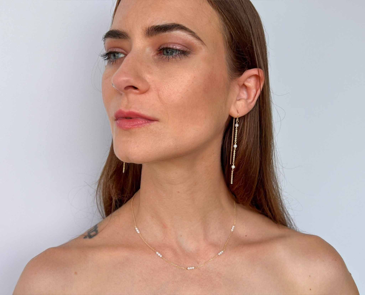 model wearing pearl station necklace or "tin cup" necklace along with matching tiny pearl chain earrings
