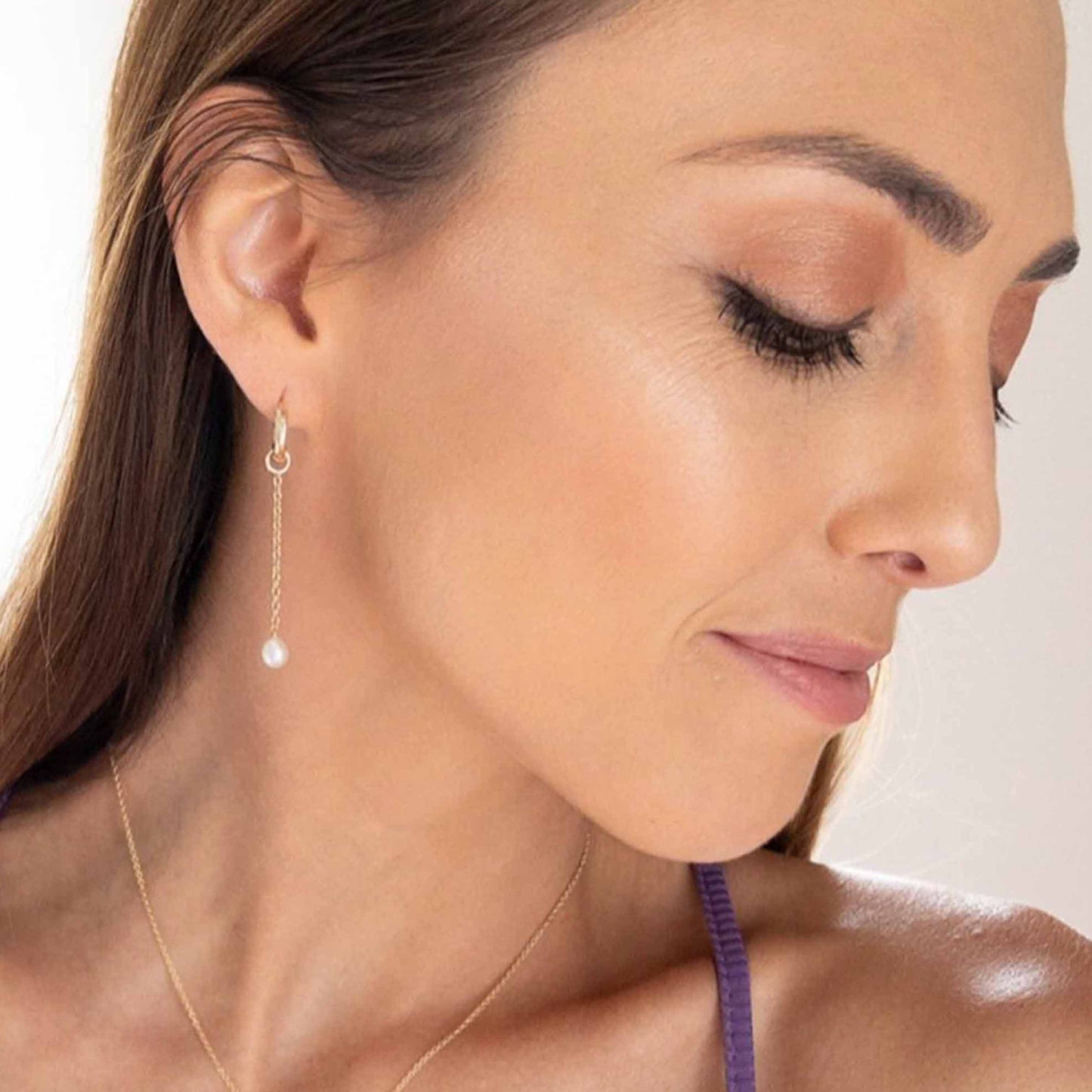 model wearing Rosa pearl dangle earrings with huggie hoops