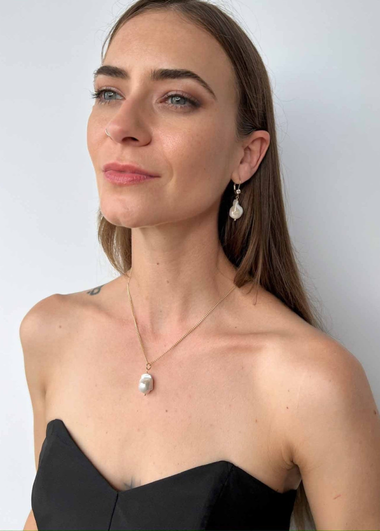 model wearing baroque pearl necklace on curb chain, along with baroque pearl earrings