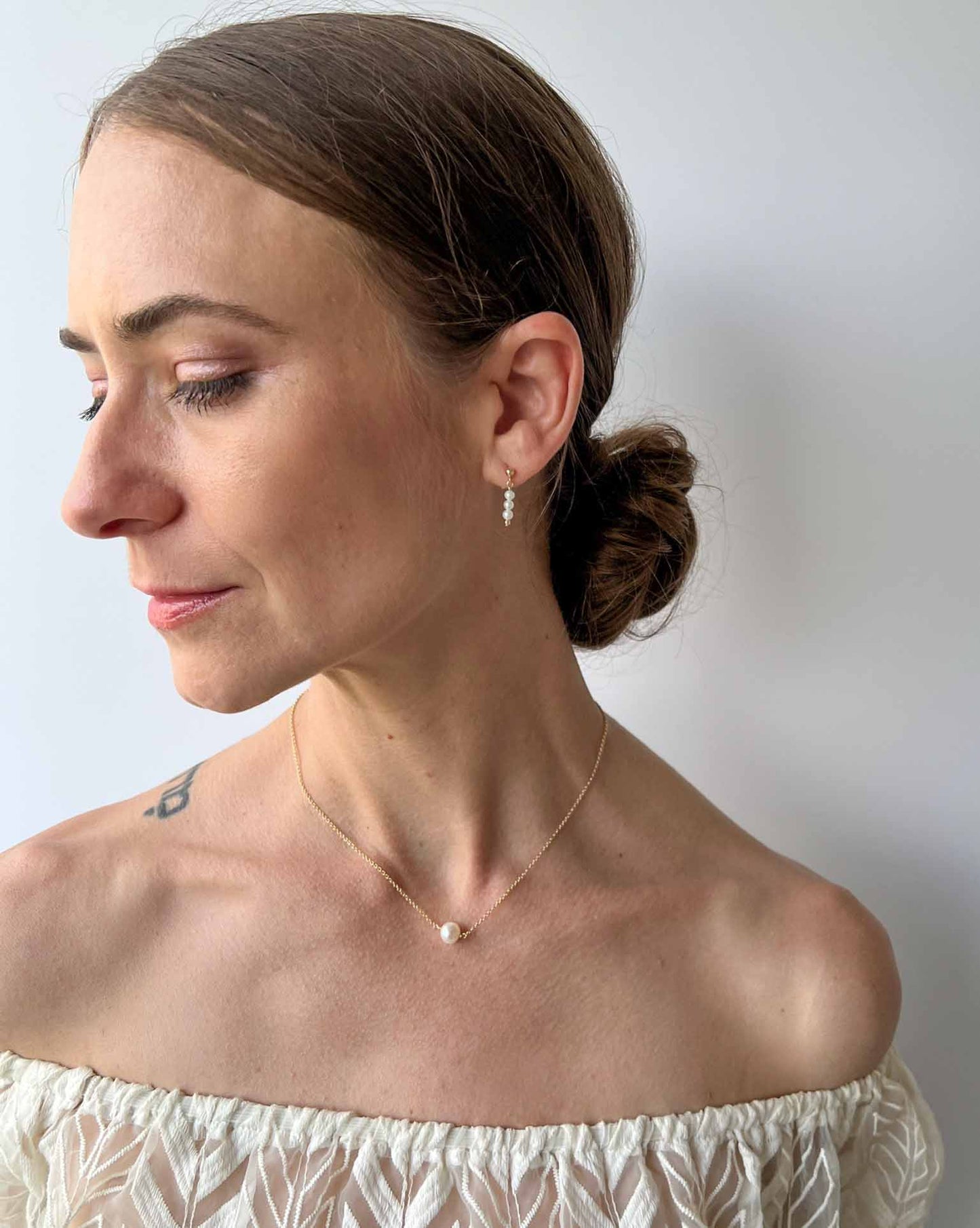 freshwater pearl dangle earrings on model with single pearl necklace