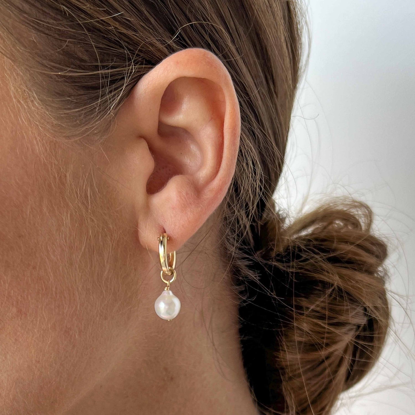 close up of model wearing Pearl huggie hoop earrings