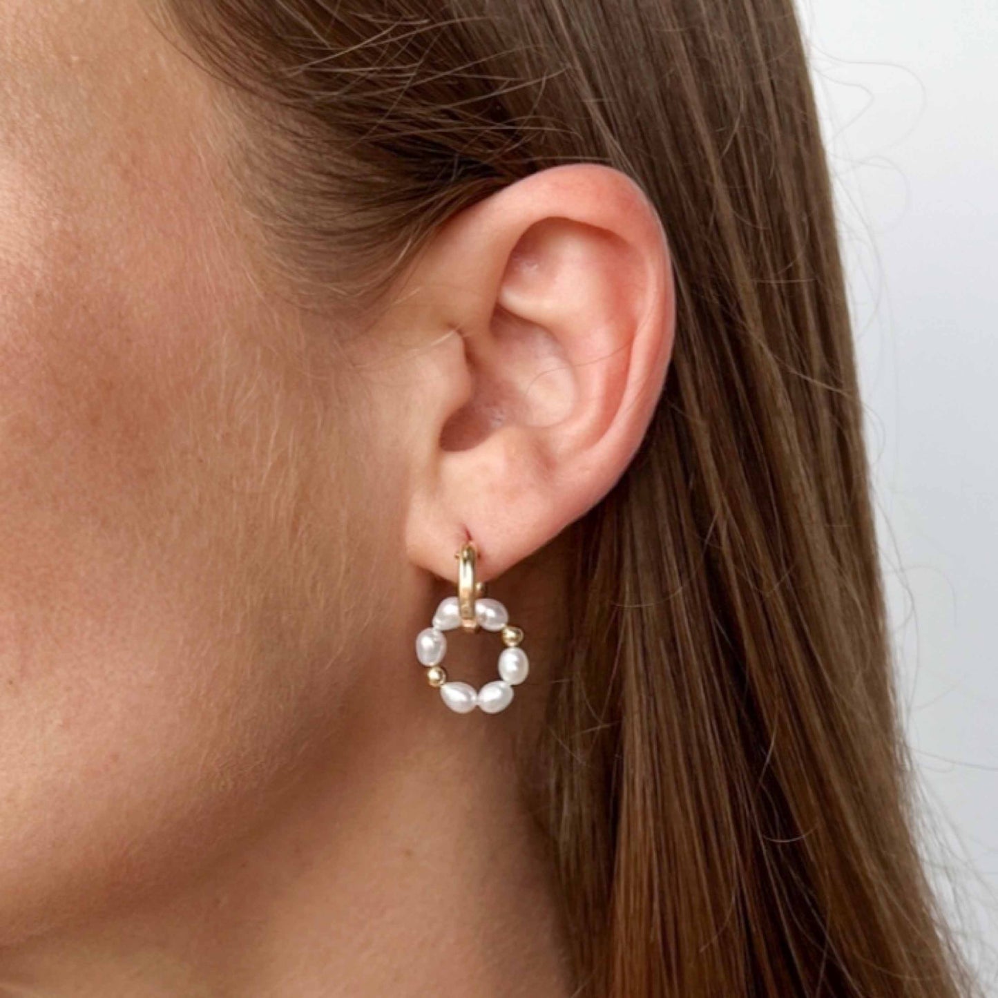 close up of Pearl Huggie Earrings on Model
