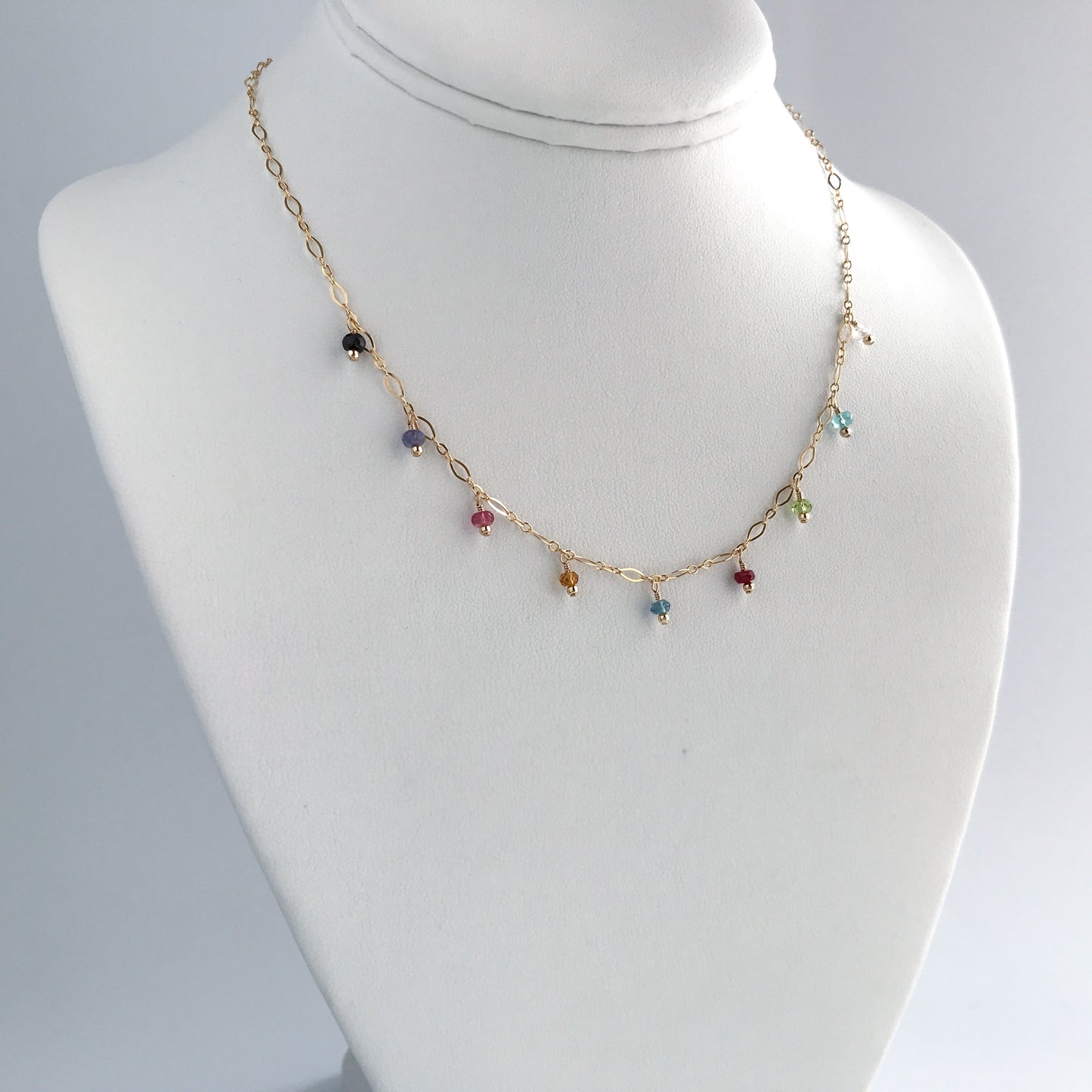 necklace stand with colorful gemstones dangling from 14k gold filled chain