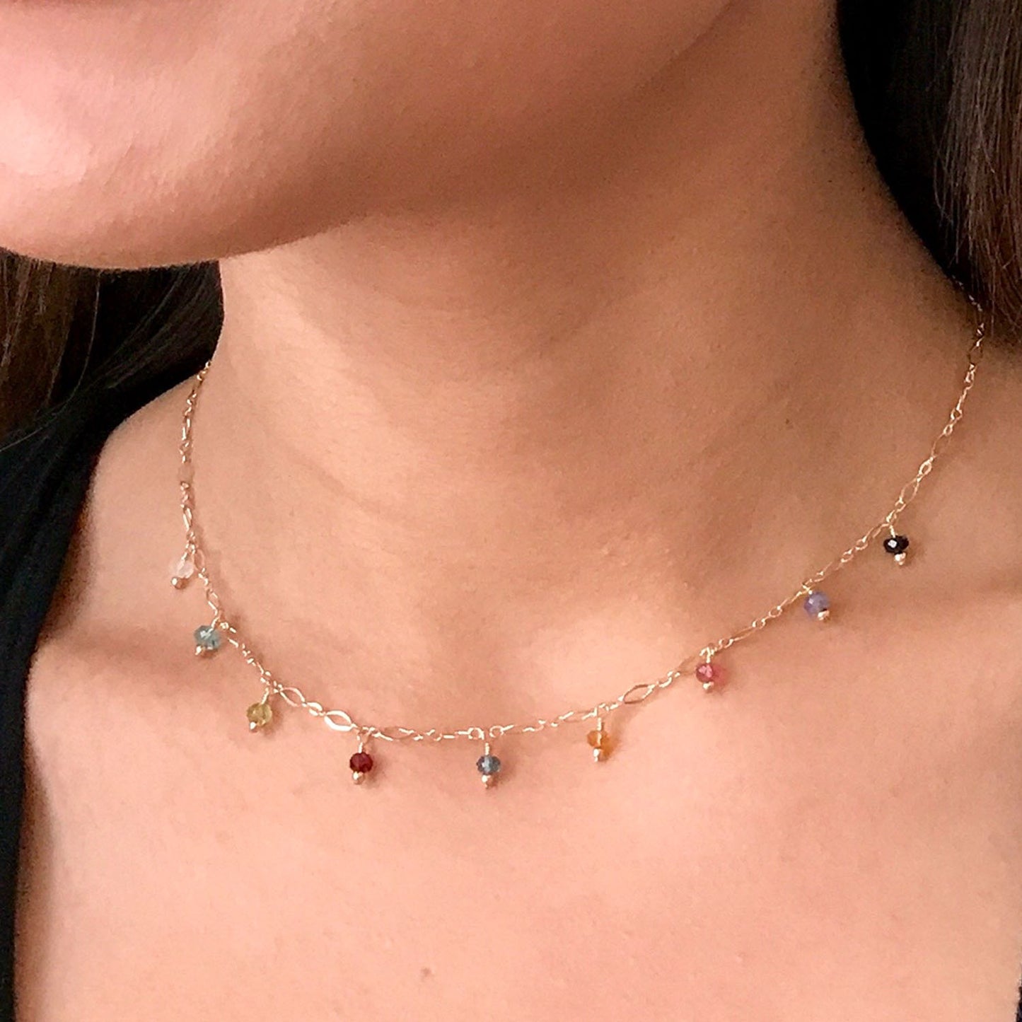 model wearing dainty gemstone necklace in gold