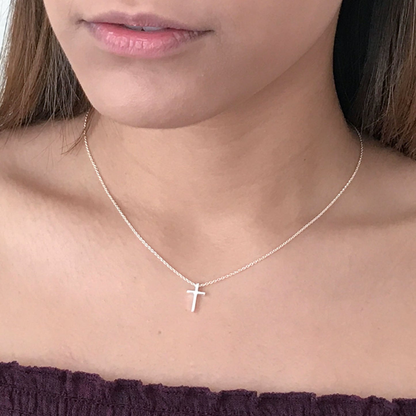 close up of model wearing tiny sterling silver cross necklace