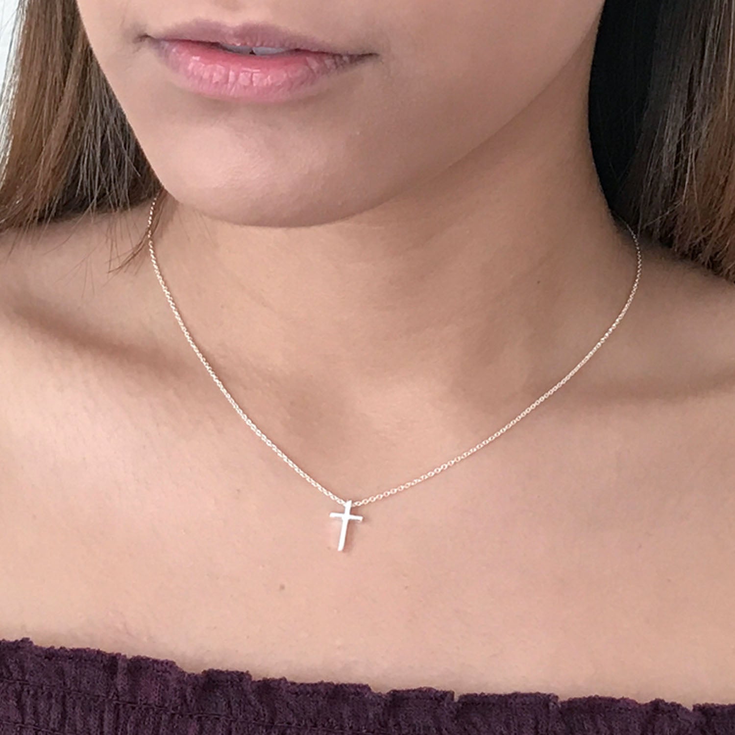 close up of model wearing tiny sterling silver cross necklace