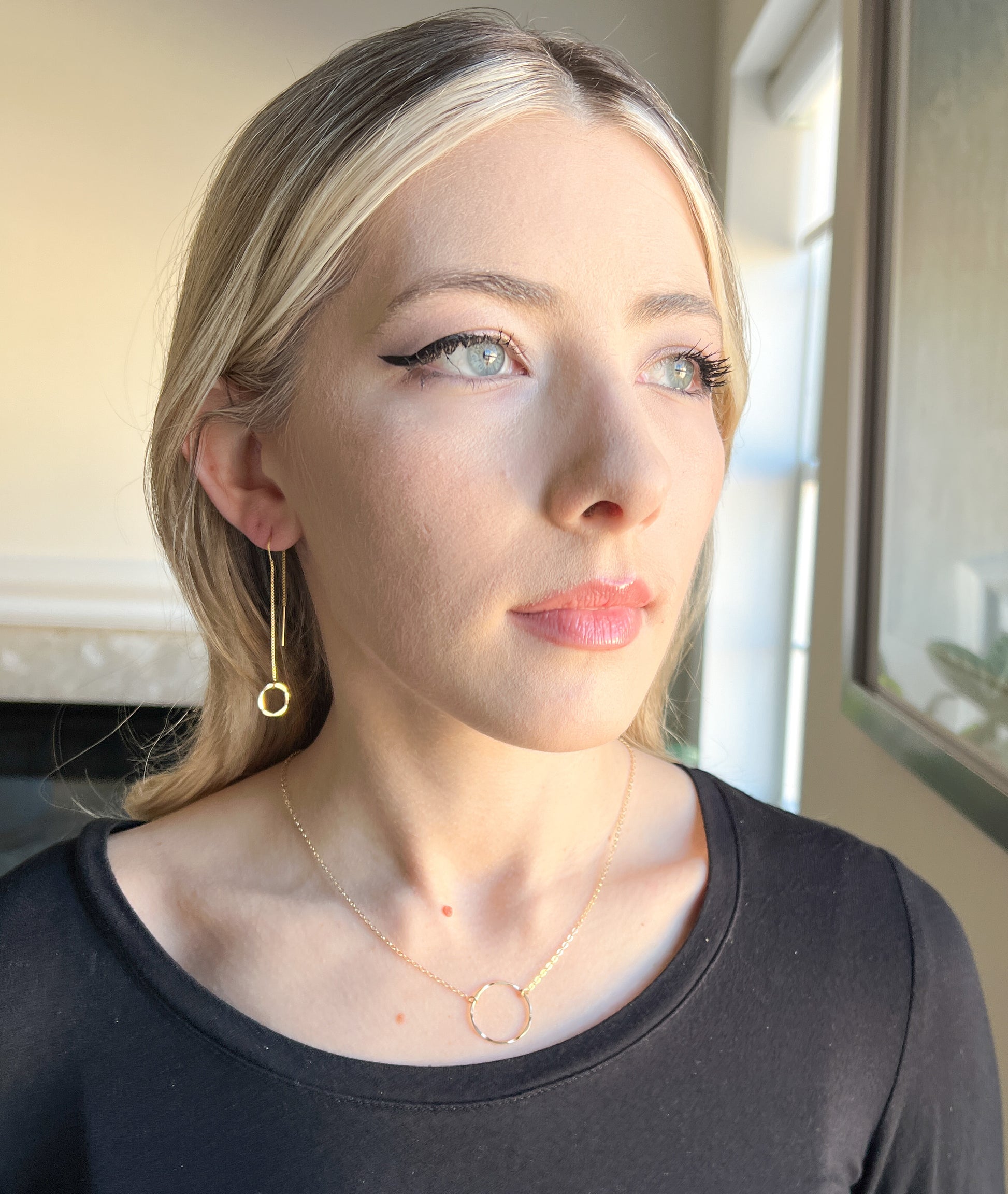 Lightweight threader earrings.  Model is wearing long dangle gold threader earrings with small gold hammered circle in front.