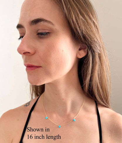 model wearing 16 inch length of turquoise necklace featuring 3 small turquoise stones stationed on a gold chain