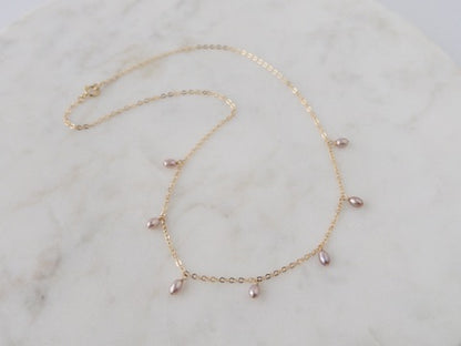 Gold necklace with pink beads on a marble surface