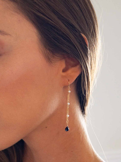 close up of model wearing pearl and sapphire threader earrings in gold