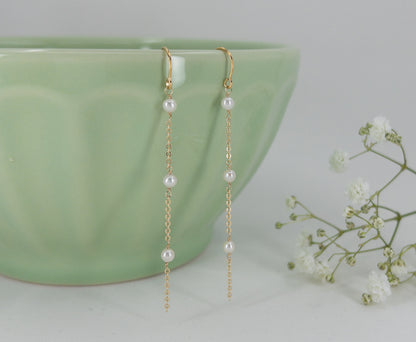 close up of pearl earrings on green bowl