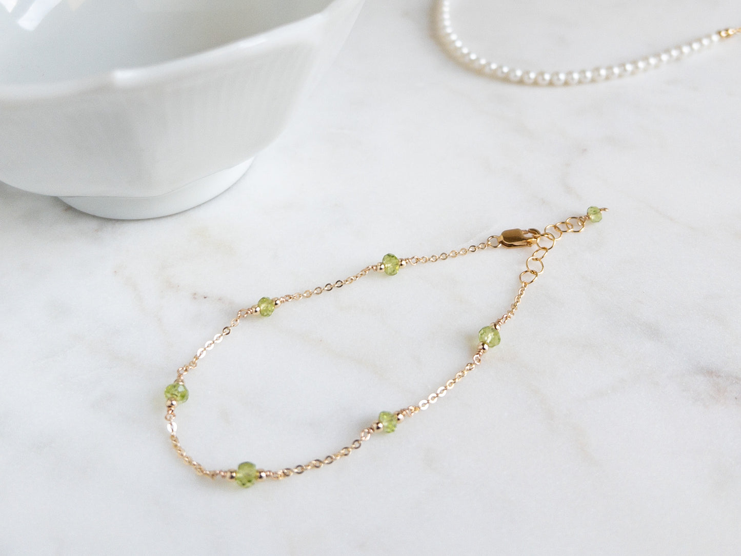 14k gold filled peridot bracelet on marble background