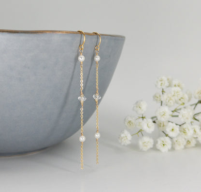 front side of threader earrings showing tiny freshwater pearls and herkimer diamond crystals hanging from blue dish