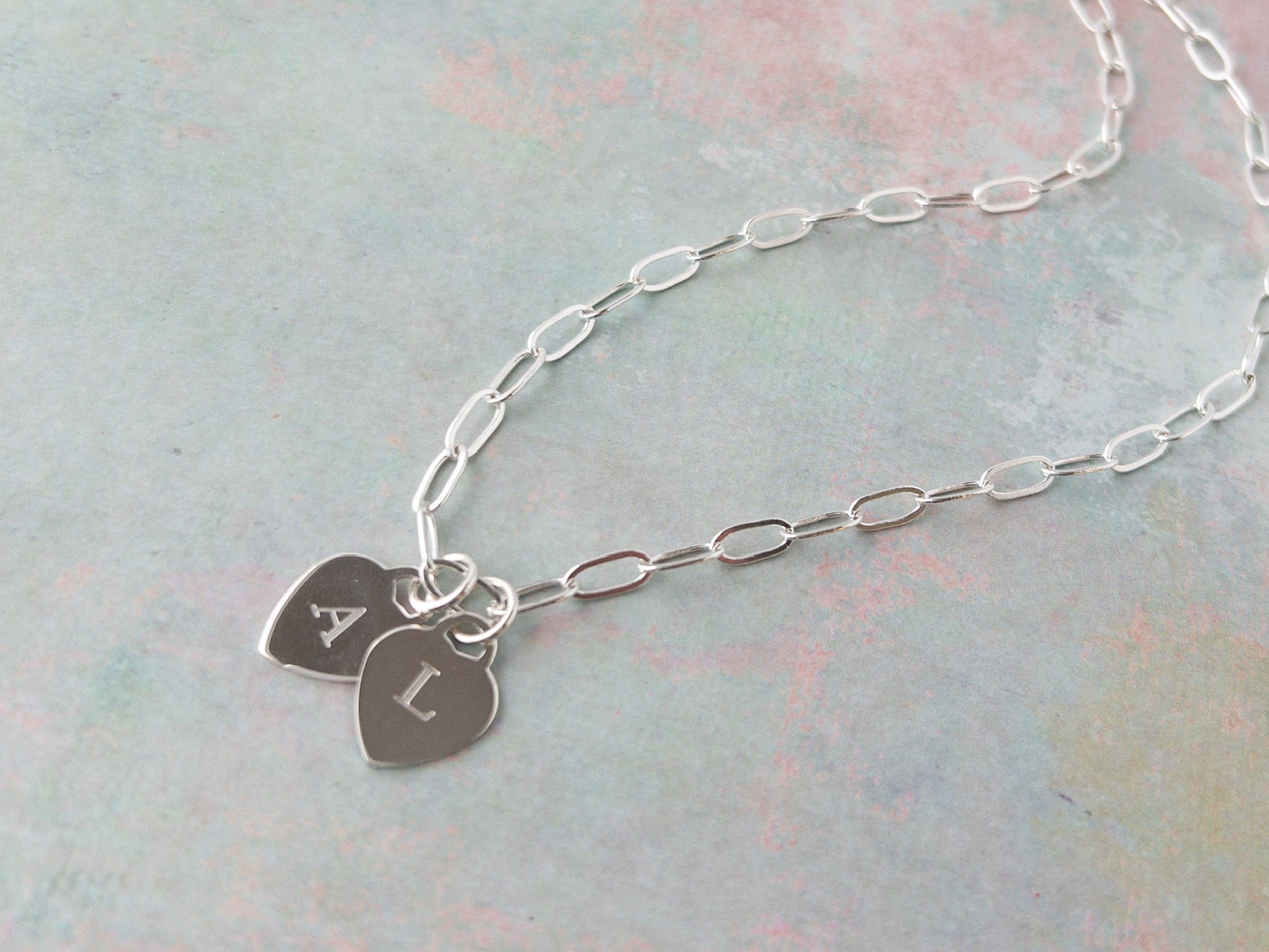 close up of sterling silver heart charms with engraved letters