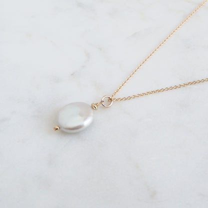 Gold necklace with a pearl pendant on a marble surface available in 16 inch, 18 inch or 20 inch length