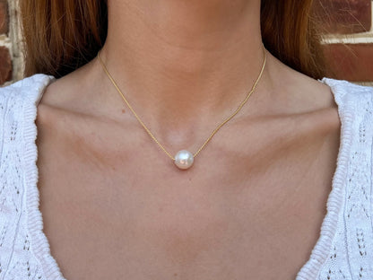 close up of model wearing single pearl necklace with large freshwater pearl floating on a chain