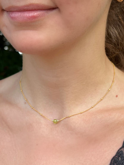 close up of model wearing peridot birthstone necklace