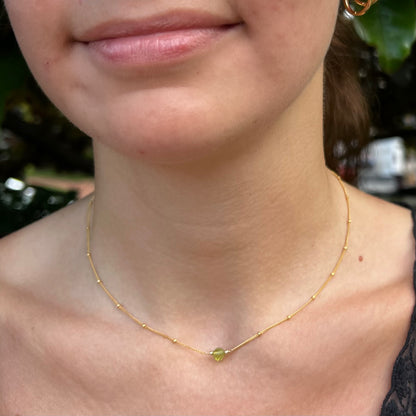 model wearing small peridot August birthstone necklace