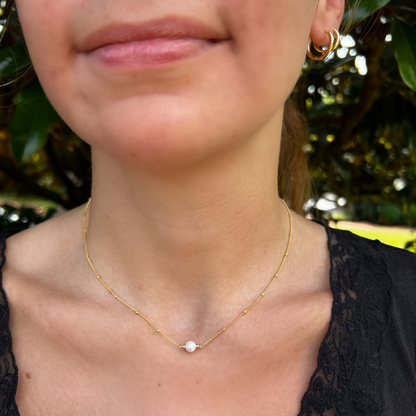 close up of single pearl necklace on gold chain