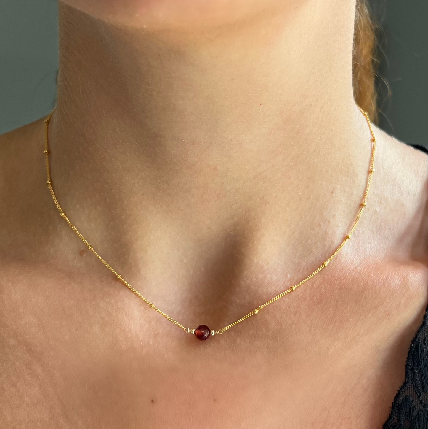 close up on model of garnet ball orbit necklace