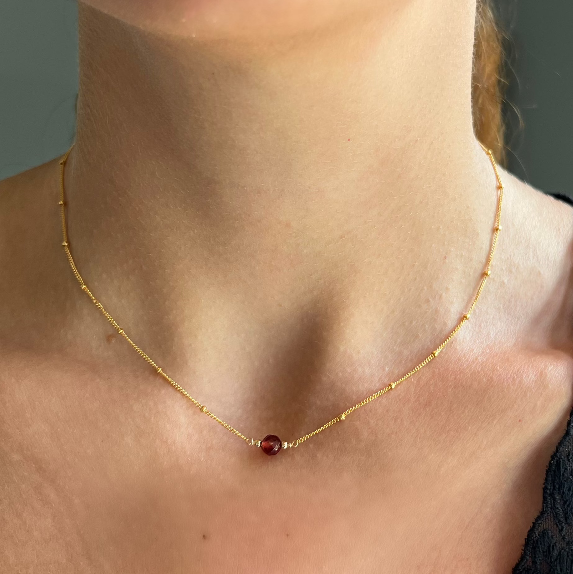 close up on model of garnet ball orbit necklace