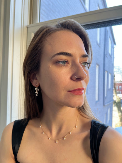 model wearing pearl dangle necklace in gold with matching pearl hoop earrings