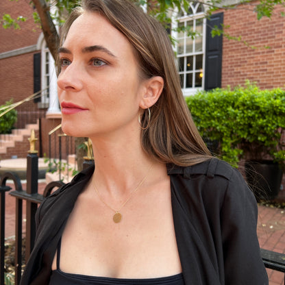 Model wearing 1.5 inch hammered hoop earrings in gold