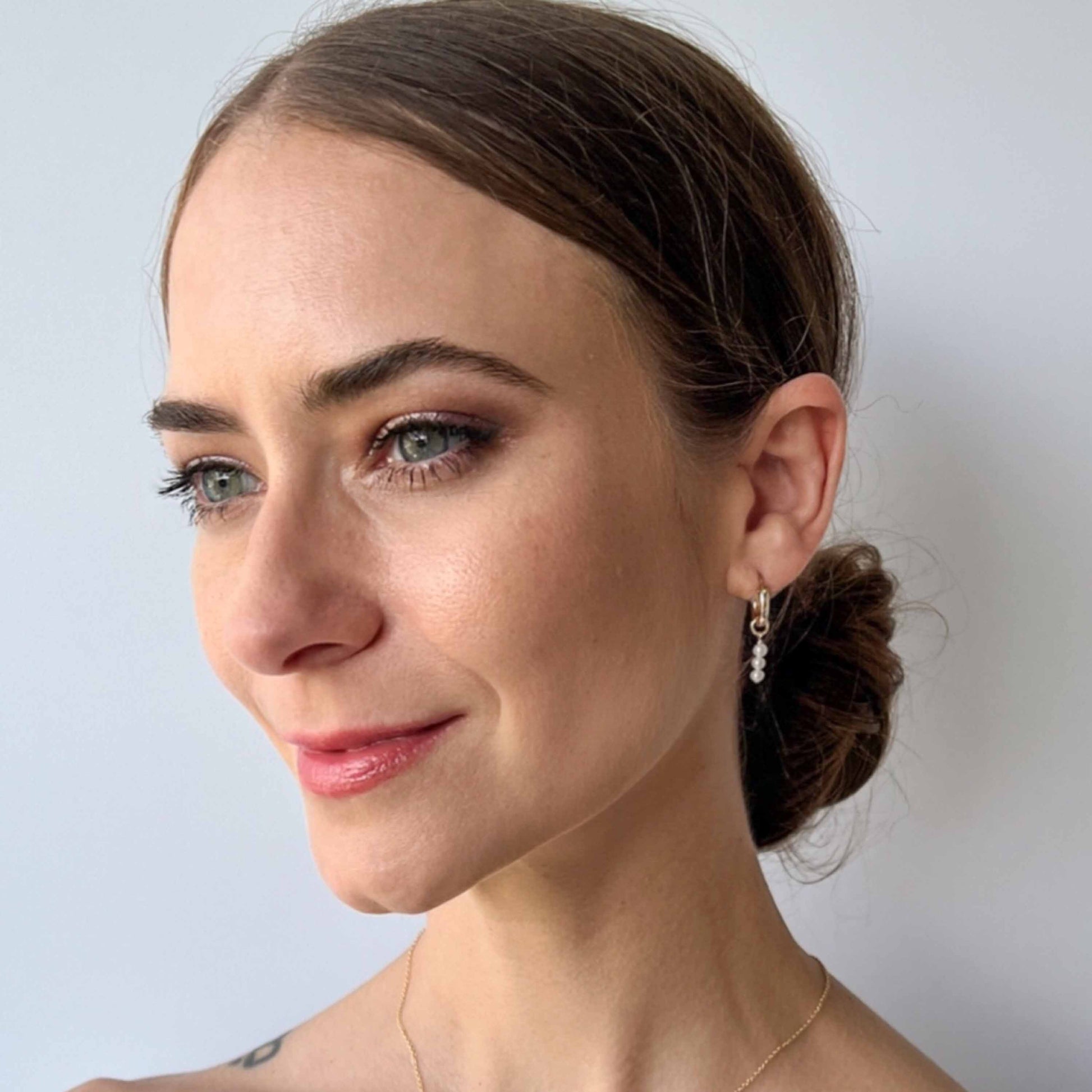 Model wearing pearl hoop earrings in gold.  Hoops have removeable pearl dangles made with freshwater pearls