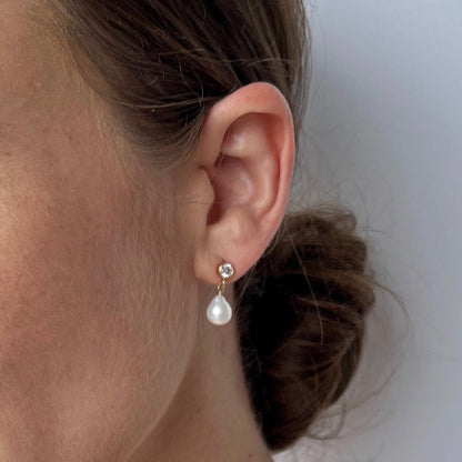 close up of model wearing Vivara Baroque Pearl Stud Earrings with cubic zirconia post earrings and a dangling pearl