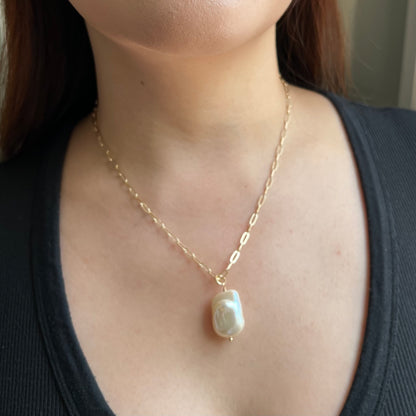 model wearing baroque pearl pendant on gold paperclip chain in 18 inch length
