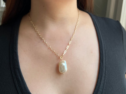 model wearing large pearl pendant on gold paper clip chain