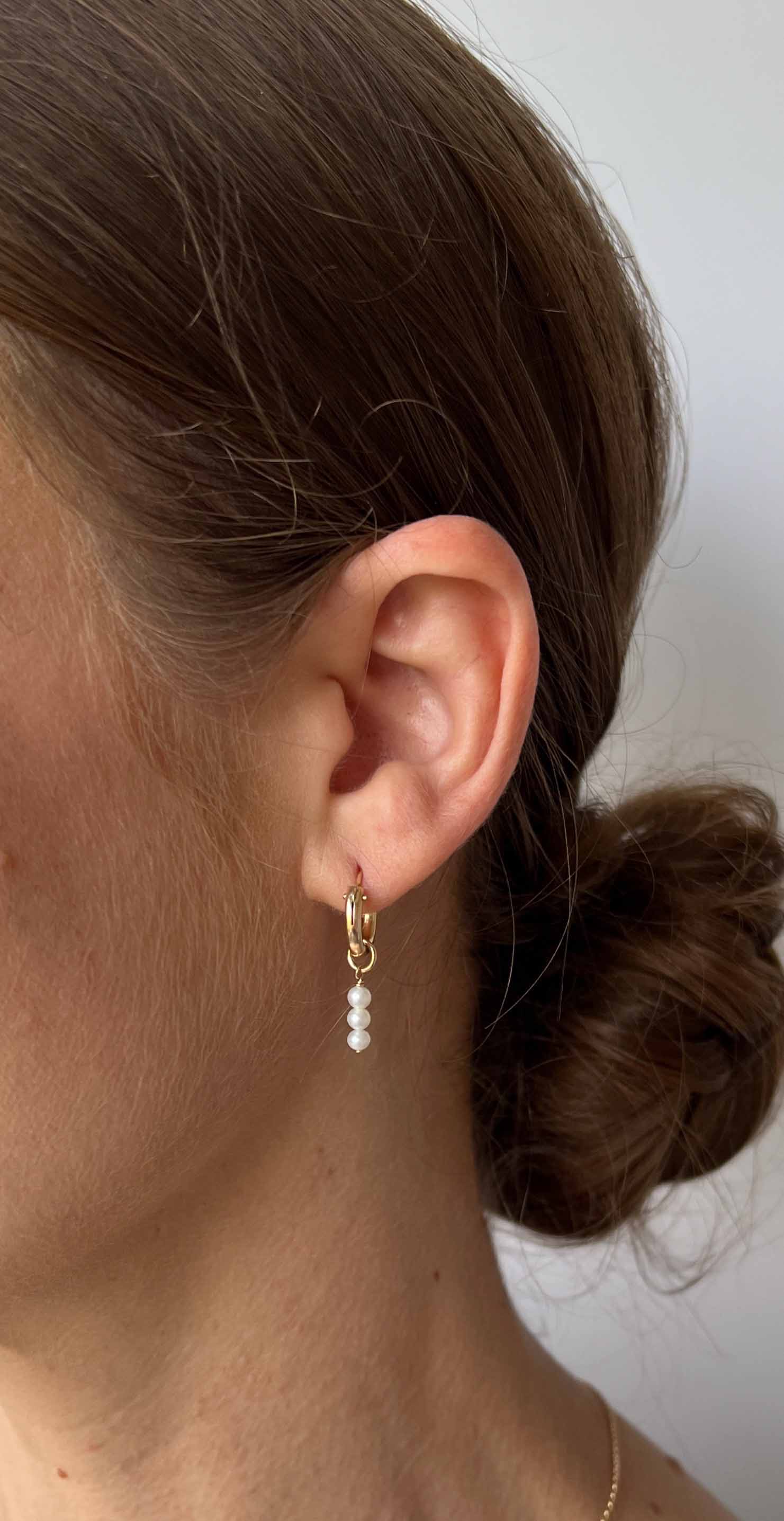 model wearing dainty pearl hoop earrings