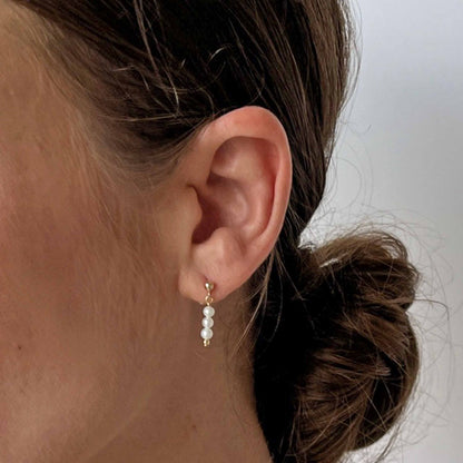 model wearing pearl drop earrings in 14k gold fill with small stud and 3 tiny pearls