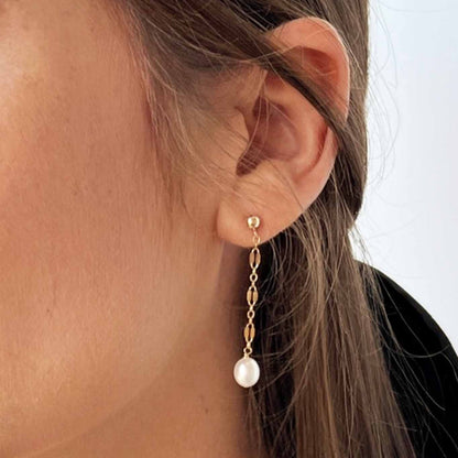close up of model wearing stud earrings with dangle pearls