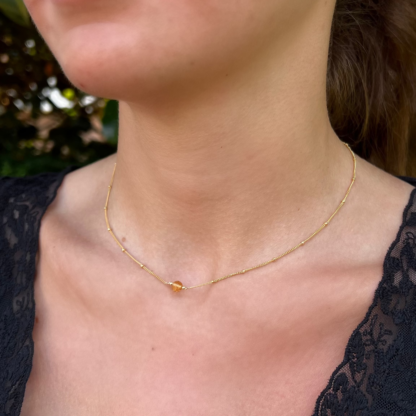 close up of model wearing citrine orbit necklace